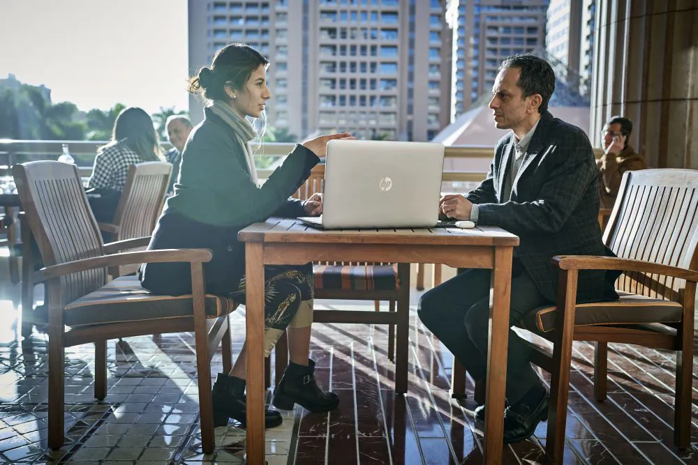 two colleagues discussing work on a laptop outside